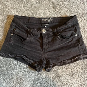Svarta jeansshorts - Snygga svarta jeansshorts från KappAhl med fransad kant. Modellen är lågmidjad och har knapp och dragkedja framtill. Vintage jeansshorts i storlek 164 men liknar S.