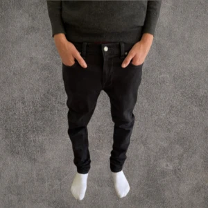 Svarta slim jeans från Nudie Jeans, w32 - Säljer ett par svarta jeans från Nudie Jeans i storlek 32/32. De har klassisk femficksdesign, svarta sömmar och Nudie-logga på bakfickan. Jeansen är raka i modellen och har en normal passform. Materialet är huvudsakligen bomull med lite elastan för extra komfort.