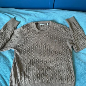Beige kabelstickad tröja från GANT XS - Säljer en beige kabelstickad tröja från GANT med rund hals och broderad logga på bröstet. Tröjan har långa ärmar och klassisk ribbad mudd vid ärmslut och nederkant. Tröjan är 10/10 skick✨Inga tecken på tidigare användning. Det är barnstorlek på tröjan (170), men sitter som Xs/S. Nypris ca 700. Skriv gärna om du har funderingar!🤗😇