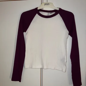 Vit och vinröd långärmad tröja Nelly - Säljer en långärmad tröja från Nelly i storlek M. Tröjan är vit med vinröda ärmar och krage, har en klassisk baseball-look och är tillverkad i mjuk bomull med lite stretch. Perfekt för dig som gillar en enkel men snygg stil.