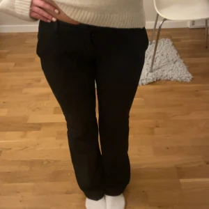 Svarta lowwaist kostymbyxor - Svarta lowwaist bootcut kostymbyxor från BikBok i stretchigt material med dragkedja och knapp framtill. Skriv om du har några frågor!!