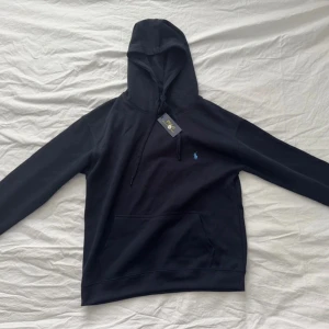 Svart hoodie från Polo Ralph Lauren M - Svart hoodie från Polo Ralph Lauren i barnstolek XL (motsvarar stl M/S) i nyskick! Aldrig använd, nypris runt 2000. Vårt pris: 999, förhandlingsbart såklart! 