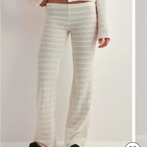 stickade byxor från Nelly  - Säljer ett par vita stickade byxor med breda ben och relaxed passform. Byxorna har en snygg virkad look och är perfekta för en chill och trendig stil. De är höga i midjan och supermjuka mot huden.