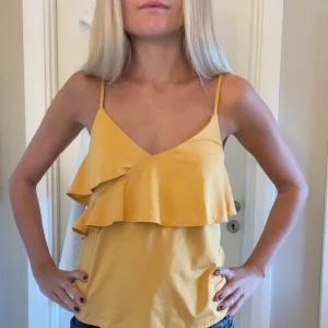 Gul volang-linnetopp med smala axelband - Superfin gul linnetopp med smala axelband och dubbla volanger framtill. 