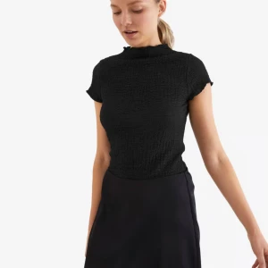 Svart topp med kort ärm och textur  - Säljer en svart topp med struktur och korta ärmar. Toppen har en hög hals och är figurnära i modellen. Perfekt att styla till olika outfits. Finns även i vit och rostfärgad om man är intresserad! 