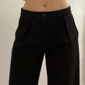 Svarta kostymbyxor från Kappahl - Snygga svarta kostymbyxor från Kappahl med klassisk passform och pressveck. Byxorna har mid waist, hällor för bälte och stängs med knapp och dragkedja. Eleganta och fina för speciella tillfällen 💕Storlek: 158