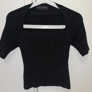 Svart glittrig topp från Karen Millen - Säljer en svart glittrig topp från Karen Millen med korta ärmar och fyrkantig ringning. Toppen har en tight passform och är perfekt för att lyfta vilken outfit som helst med sitt diskreta glitter. Superfin att styla till både jeans och kjol!