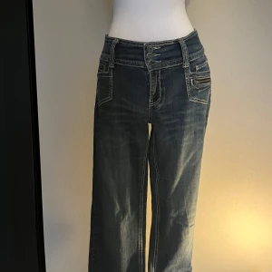 Blå jeans med dubbla knappar och raka ben - Snygga blå jeans med låg midja och raka ben. Jeansen har dubbla knappar. Står ingen lapp men passar mig som har S-M i storleken