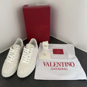 Vita Valentino Garavani sneakers - Säljer ett par stilrena vita sneakers från Valentino Garavani. Skorna har klassisk design med rund tå, platt sula och diskret logga på sidan och innersulan. Perfekta för dig som gillar lyxiga och minimalistiska sneakers. Använda fåtal gånger. Nypris 7280kr! 