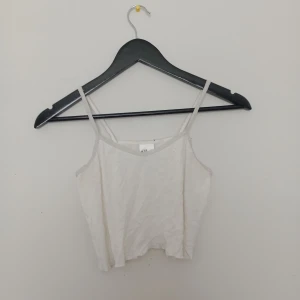 Vit croppad linnetopp - Säljer en enkel och stilren vit croppad linnetopp från H&M. Toppen har smala axelband och är perfekt för varma dagar. Passar dig som gillar minimalistisk stil.
