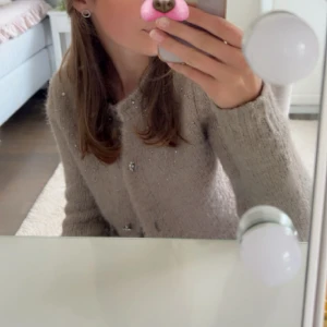 Beige stickad kofta med pärlknappar - Superfin beige stickad kofta med pärlknappar, har även pärlor upptill. Koftan har lång ärm och en klassisk rund halsringning. (Fixar bättre bild snart!) Sällan använd så i mycket fint skick. 🥰