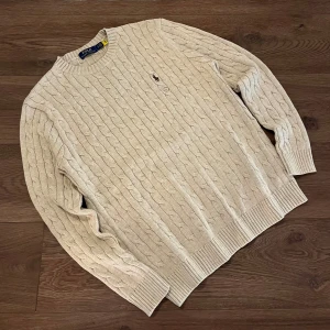 Polo Ralph Lauren Beige stickad tröja  - Säljer en klassisk beige kabelstickad tröja från Polo Ralph Lauren. Skick är 10/10. Den är aldrig använd, ändas testad. Säljer för att den var för stor för mig. Storlek S men passar även som M. Riktigt stilig och matchar med det mesta. Priset går att diskuteras vid snabbt affär