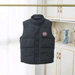 Svart dunväst från Canada Goose - Säljer en svart dunväst från Canada Goose med hög krage och två stora fickor framtill. Västen har ett broderat märke på bröstet och stängs med både dragkedja och knappar. Perfekt för kyliga dagar. Inte använd och perfekt som sommarväst!