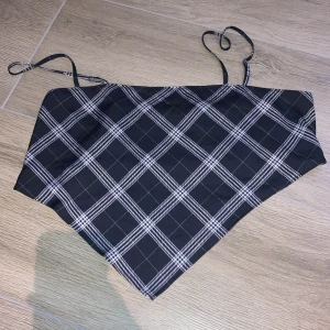 Svart och vit rutig croppad linnetopp från H&M Divided - Säljer en svart och vit rutig croppad linnetopp från H&M Divided. Toppen har smala axelband och ett smockat parti på baksidan för extra komfort. Perfekt för sommaren och enkel att matcha med jeans eller kjol.