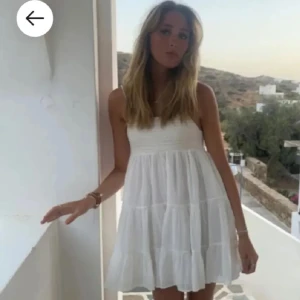 Vit sommarklänning från Gina Tricot - Supersöt vit klänning med smock upptill och tunna axelband. Klänningen har en luftig, volangig kjol och är perfekt för varma dagar. 