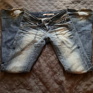 Blå slitna jeansbyxor från only - Säljer ett par blå jeansbyxor från ONLY med slitningar och ljusa tvättade partier. Byxorna har fem fickor, dragkedja och knapp framtill samt klassiska bakfickor. Märkeslapp bak i midjan och detaljerade sömmar. Förutom att jag gått på som så dom är slitna längst vid fötterna är dom i bra skick!💞