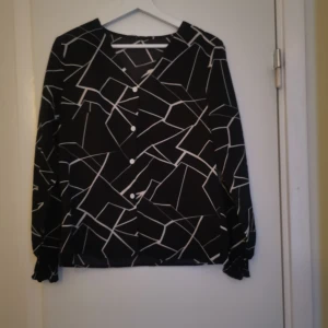 Blus - En svart snygg blus med vitt mönster. 