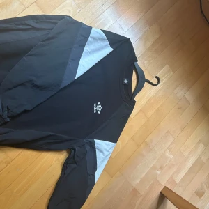 Svart långärmad tröja från Umbro - Retro umbro tröja som är väldigt sällsynt och går inte att få tag på längre. Använd endast fåtal gånger och har inga defekter. Den har vanligt material på mage och rygg, men vid ärmarna har den lite regnjacke material vilket gör den extra unik, det står att den är i storlek 100, men sitter som en M. Skulle säga att den passar från 173-183