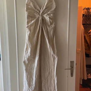Beige långklänning från Zara - Säljer en supersnygg beige långklänning från Zara med strukturer/detaljer i tyget. Klänningen har tunna axelband, slits framtill och dragkedja i sidan💗