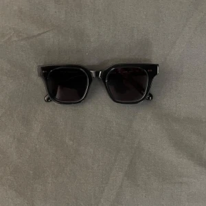 Svarta solglasögon från CHIMI - Snygga svarta solglasögon från CHIMI med rektangulära bågar i blank plast. Modellen är markerad och passar perfekt för dig som gillar en stilren look. Kommer med originalfodral. Kvitto finns 