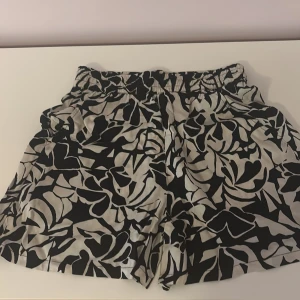 Svartvita mönstrade shorts från Lindex - Snygga svartvita shorts från Lindex med elastisk midja och abstrakt blommigt mönster.  Med prislapp på.Tillverkade i ett mjukt och lätt material, perfekta för varma dagar. Shortsen har en avslappnad passform och är supersköna att bära.