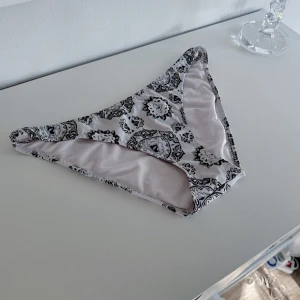 Mönstrad bikiniunderdel - En mönstrad bikiniunderdel i storlek 40 från H&M SWIMWEAR som enbart är tvättad och tyvärr fick dom ett slitage (se bild 2). Nypris 129kr! FÖRST TILL KVARN!