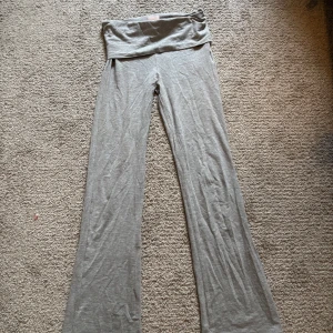 Gråa vida yogabyxor med låg midja - Superbekväma grå yogabyxor med låg midja och utsvängda ben. Perfekta för träning eller avslappning. Mjukt och stretchigt material som ger en skön känsla hela dagen.