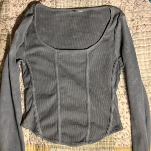 Ljusblå/grå ribbad långärmad topp/ corset - Andvänd 1 gång 2023. Säljer en ljusblå/grå långärmad topp med ribbad struktur och fyrkantig urringning. Toppen har figurnära passform och markerade sömmar framtill som ger en snygg siluett. Perfekt att styla med jeans eller kjol!
