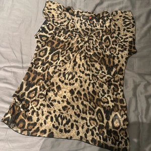 Leopardmönstrad blus från ONLY - Säljer en snygg blus från ONLY med leopardmönster i beige, brunt och svart. Blusen är ärmlös med lätt volang vid axlarna och har en luftig passform. 