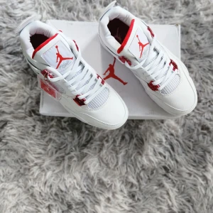 Nike Air Jordans vita och röda sneakers - Säljer ett par fräscha Nike Air Jordans i vitt med röda detaljer. Skorna har klassisk snörning, rund tå och platt sula. Ikonisk Jumpman-logga syns tydligt på plös och sula. Perfekta för dig som gillar streetwear och sneakers med stil.