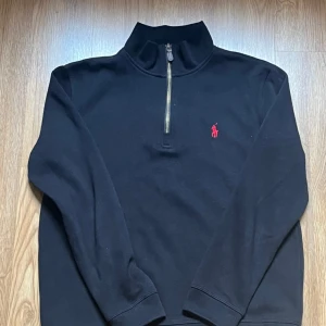 Svart halvzip tröja från Polo Ralph Lauren - Helt ny tröja – aldrig använd! Säljer den för att den är lite för liten på mig. Superfräsch och i perfekt skick. Passar dig som har en mindre storlek. Hör av dig vid frågor! 