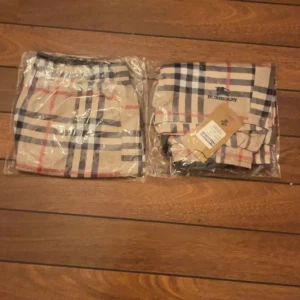 Burberry shorts - Snygga Burberry shorts i klassiskt beige rutigt mönster med svarta, vita och röda ränder. Shortsen har elastisk midja med svart snörning och sidofickor. Perfekta för sommaren och har en sportig vibe. Shortsen är helt nya och aldrig använda. 