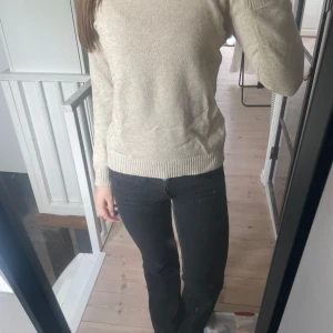 Beige stickad tröja - Säljer en enkel och stilren beige stickad tröja med rund halsringning och långa ärmar. Tröjan har ribbade muddar vid ärmslut och nederkant, perfekt för lager-på-lager under kyligare dagar. Tröjan är ifrån vila.