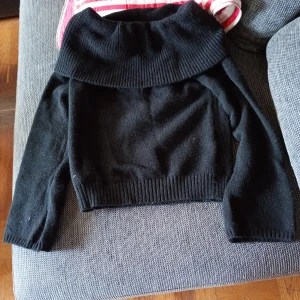 Svart stickad polotröja stl L  - Säljer en svart stickad polotröja med bred polokrage och långa ärmar. Tröjan har en croppad passform och ribbade muddar vid ärmslut och nederkant. Perfekt för lager-på-lager och snygg till både jeans och kjol.