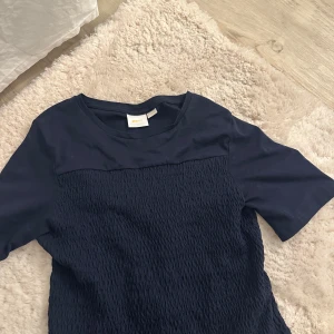 Mörkblå  topp med volang - Säljer en mörkblå topp med volanger ner till. Trendig topp. Den är köpt från Gina tricot Young, har den i storlek 158/164.🥰🥰