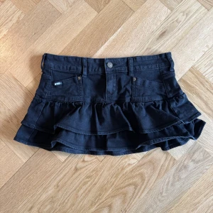 Jeanskjol - Svart jeanskjol, aldrig använd med lappen kvar från Minga London. S-XS. Ca 37 cm rakt över midjan.