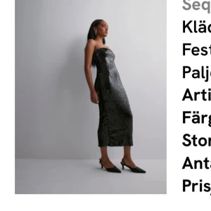 Svart paljettklänning med slits - Säljer en svart axelbandslös paljettklänning i midi-längd. Klänningen har en tight passform och en snygg slits bak. Perfekt för dig som vill sticka ut med glittriga detaljer och elegant siluett.