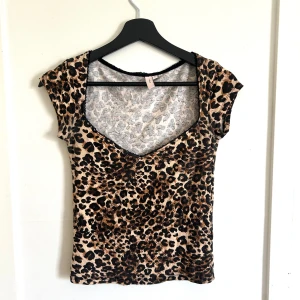 Leopardmönstrad topp med v-ringning - Snygg leopardmönstrad topp med v-ringning. Materialet är stretchigt och följsamt.. Passformen är tight. Använd vid max ett tillfälle men är som ny! 