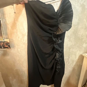 Svart asymmetrisk klänning med volang - Asymmetrisk klänning som passar bra till fest 🖤 säljs då den blivit för stor men annars är det en stor favorit. Passar S