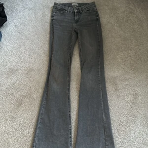 Grå bootcut jeans från ONLY - Säljer ett par gråa bootcut jeans från ONLY i storlek XS. Jeansen har klassisk femficksdesign, normal passform upptill och utsvängda ben. Tillverkade i denim med knapp och dragkedja framtill.