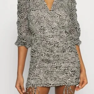 leopard mönstrad klänning från gina tricot - Säljer en snygg kortklänning från gina tricot i vit och svart med leopardmönster. Klänningen har v-ringning, trekvartsärm och omlott-design. Perfekt för dig som gillar trendiga och unika plagg. Klänningen är oanvänd och säljer den då jag fick den som present men inte passade.