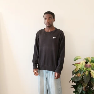 Svart sweatshirt från Lotto - Svart sweatshirt från Lotto med rund halsringning och diskret logga på bröstet. Tröjan har långa ärmar och ribbade muddar vid ärmslut och nederkant. Enkel och stilren design som passar till många tillfällen. Svart tröja med vit logga på bröstet. Tröjan har vita ränder på axlarna.  Lotto sweatshirt   Size L (fits M)  Feel free to ask any questions   Length:68cm Chest:57cm Arm-Length:63cm