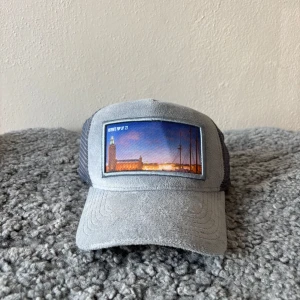  Revenite popup keps - Snygg grå keps från Revenite med mesh på sidorna och ett broderat motiv av Stockholms stadshus framtill. Perfekt accessoar för dig som gillar stilrena detaljer och stadsmotiv. Nypris 450kr från Revenites egna butik, mitt pris endast 249kr men kan diskuteras vid snabb affär 