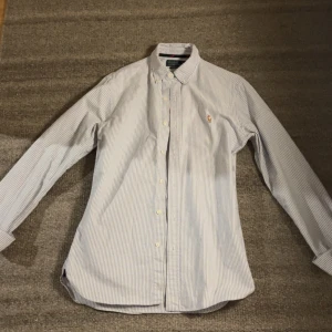 Randig skjorta Polo Ralph Lauren S - Klassisk slim fit skjorta från Polo Ralph Lauren i vitt och blått med tunna ränder. Är för stor för mig som är 175 så om du är 180 eller längre passar den perfekt🤩 priset går självklart att diskutera!!! Bara att höra av sig😀