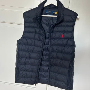 Mörkblå väst från Polo Ralph Lauren - Mörkblå väst från Polo Ralph Lauren. Storlek M. Väldigt fint skick, inga defekter eller skador på västen. 