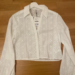 Vit broderad skjorta från Zara - Superfin vit skjorta från Zara med broderat mönster. Skjortan har långa ärmar och knappar framtill. Perfekt till sommaren med sitt tunna bomullstyg och snygga detaljer. Aldrig använd och har prislappen kvar! Original pris 375 men säljer för 350, pris kan diskuteras vid snabbaffär!💞