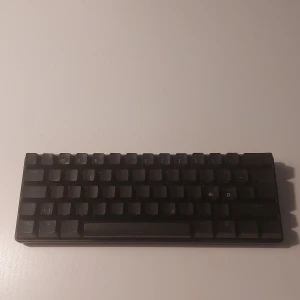 Steelseries apex pro mini  - Bilderna visar ett kompakt mekaniskt tangentbord med RGB-belysning och USB-kabel. Tangentbordet är perfekt för gaming eller studier, med snygg bakgrundsbelysning som lyser upp i mörkret. Passar dig som vill ha en stilren och portabel setup. Kabeln medföljer för enkel anslutning.