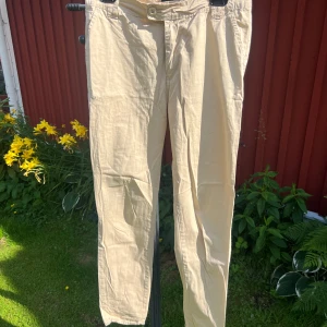 Beiga chinos från Gina Tricot - Beiga chinos från Gina Tricot i storlek 38. Byxorna har raka ben, klassisk passform och stängs med knapp och dragkedja. 