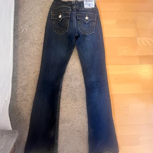 True Religion  jeans  - Supersnygga mörkblå jeans från True Religion med bootcut  och låg midja. Använt fåtam gånger, säljer då de sitter lite tajt💖Står ingen storlek på men gissar att den är 32-34