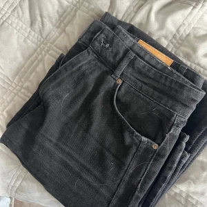 Svarta jeans från Zara - Säljer ett par svarta jeans från Zara med klassisk femficksdesign och snyggt läderpatch bak i midjan. Jeansen har raka ben och är tillverkade i ett slitstarkt bomullstyg med lite stretch. Perfekta till sneakers eller boots.